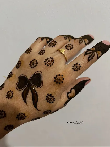 A playful and cute design with a large bow on the back of the hand, surrounded by small, scattered flowers.