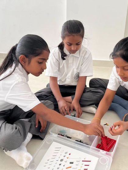 A group of girls from Sadhu Vaswani International School work together on their LEGO project, sharing ideas and pieces.