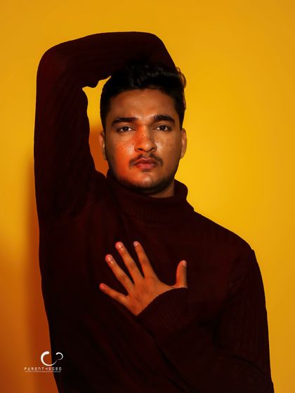 A simple, direct pose with a hand on the chest. The red light adds a touch of warmth and emotion to this otherwise minimalist portrait.