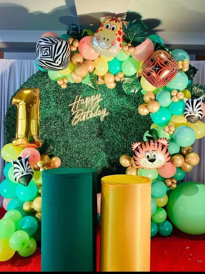 A vibrant jungle-themed balloon ring against an artificial grass wall. This setup uses animal-shaped foil balloons like a tiger, zebra, and giraffe to create a fun and lively backdrop.