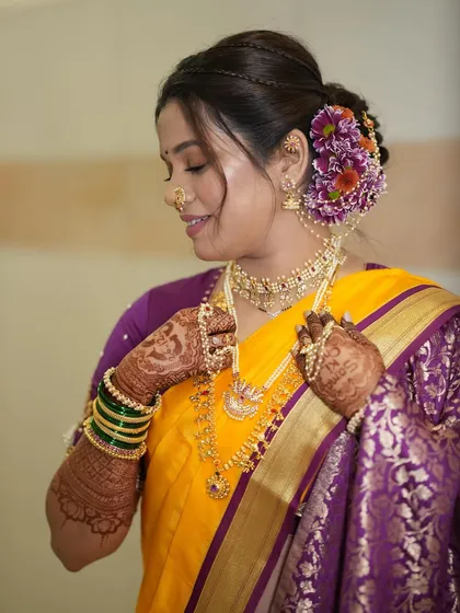 The bride admires her intricate jewelry. This shot highlights the detailed henna, green bangles, and glowing makeup.