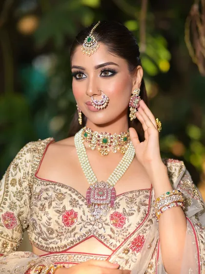 A look full of regal elegance. This close-up shot highlights the stunning contrast between the bold, smoky eye and the delicate floral embroidery on the ivory lehenga.