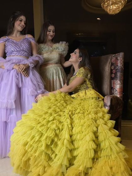A playful group shot featuring the yellow and lavender ruffle gowns. These dresses are perfect for mehendi events, sangeets, or photoshoots where you want a pop of color and texture.