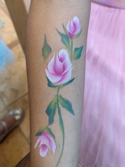 A classic painting of pink rosebuds on a vine, climbing up the arm.