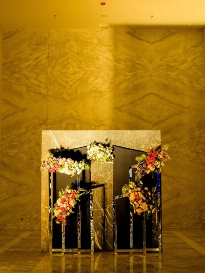 A modern and minimalist floral installation with a gold-leaf backdrop, setting a chic and artistic tone for a cocktail evening.