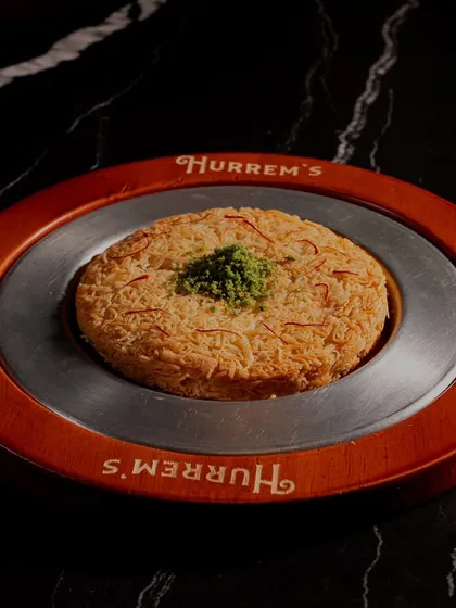 A beautifully plated Kunafah from Hurrem's Baklava. The lighting is carefully controlled to highlight the golden, crispy texture of the dessert, making it perfect for an online menu.