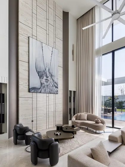 Another view of the double-height living room, showcasing the grand scale and the way natural light fills the space. The large abstract artwork and minimalist furniture maintain a sense of modern sophistication amidst the architectural volume.