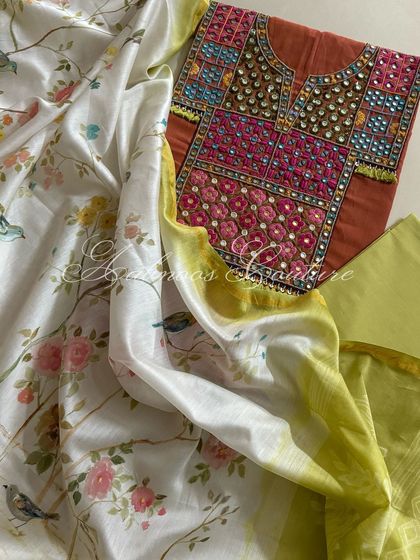 A beautifully composed shot showing the rust kurta and its accompanying lime green bottom fabric, draped with the elegant hand-painted dupatta.