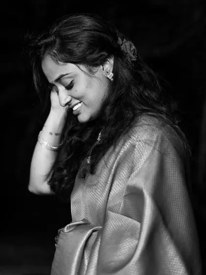 A candid black and white shot of the model smiling with her eyes closed, creating a feeling of pure, simple joy.