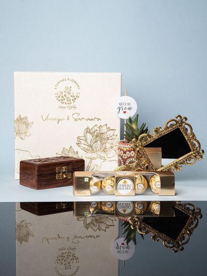 The complete naming ceremony return gift set, with the custom box reflected on a glossy surface, highlighting its luxury appeal.