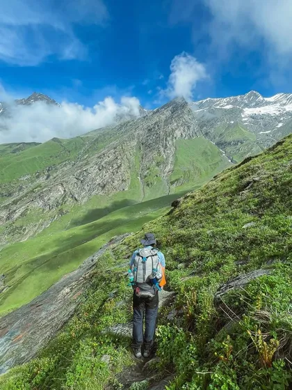 A lone trekker on the path to Beas Kund, surrounded by the vastness of the Himalayan landscape. This is what finding yourself feels like.