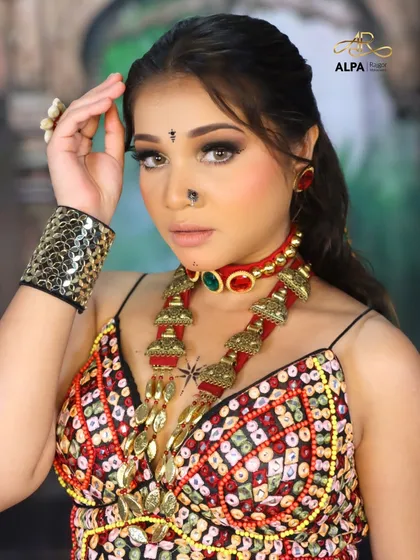 A powerful pose that highlights the bold makeup and the traditional accessories.