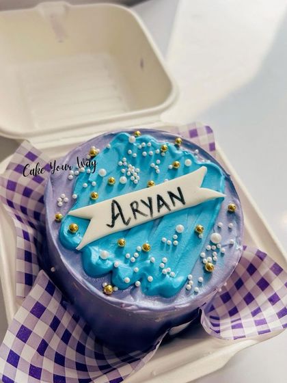 This personalized bento cake is packed in its signature takeaway box. The simple yet elegant design with a name banner, sprinkles, and a beautiful purple and blue color scheme makes it a perfect personal treat.
