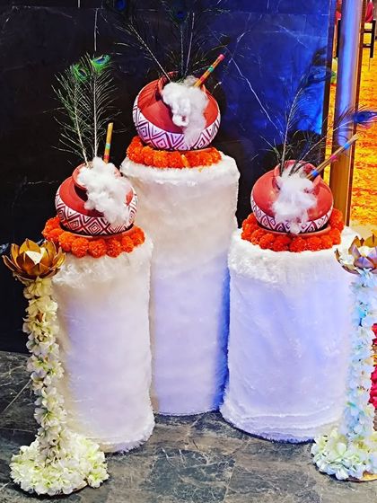 Decorative 'dahi handi' props for a Krishna-themed event. These details, featuring peacock feathers and marigolds, enhance the authenticity of the celebration.