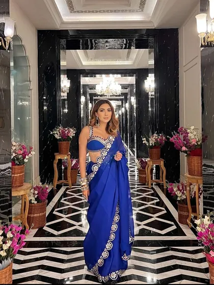 A full view of the magnificent floral lined corridor. The symmetrical arrangement of flowers and the opulent chandeliers create a grand and royal pathway for guests to enter the event.