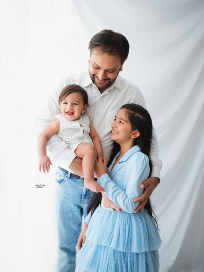 A proud father with his two children. The baby's big smile and the sweet interaction with his older sister create a delightful and heartwarming family moment.