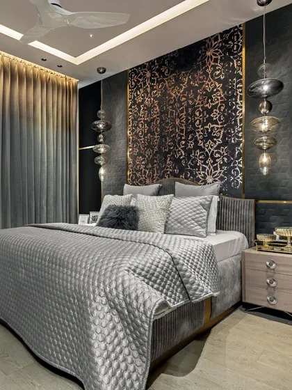 A masterclass in craftsmanship, this bedroom features a dark, moody palette with a custom damask-patterned headboard panel. The quilted grey bedding and unique glass pendant lights add layers of texture and luxury.