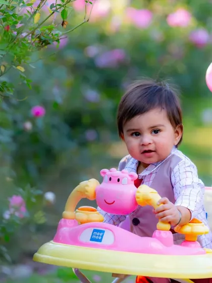 A baby enjoying the garden in a colorful walker. Outdoor sessions in locations like a rose garden provide a beautiful and natural setting for kids photography.