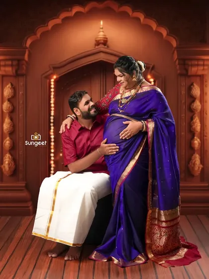 An intimate moment where the father-to-be lovingly cradles the baby bump, seated beside his wife in a traditional setting.