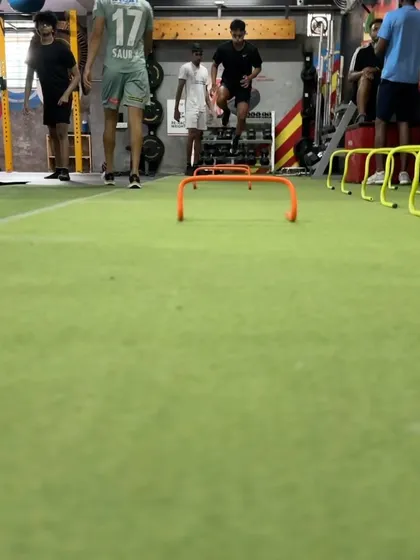 Athletes perform plyometric hurdle jumps. Plyometrics are crucial for improving speed, acceleration, and the ability to change direction explosively.