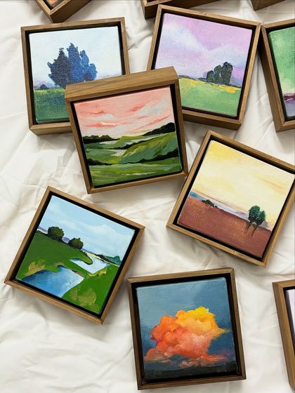 A selection of my miniature landscape paintings. These small, framed canvases capture fleeting moments in nature, from rolling hills under a pink sky to a single tree against a dramatic, cloudy backdrop.