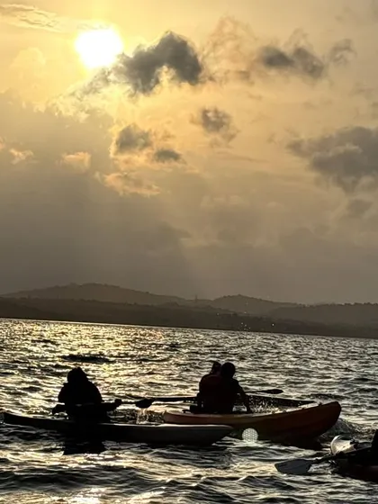 Kayakers pause to watch the sun set over the water. These serene moments are just as much a part of the adventure as the paddling itself.