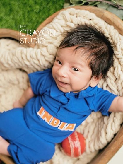 Our little champion is awake. A happy, smiling newborn in his cricket gear, ready to win hearts.