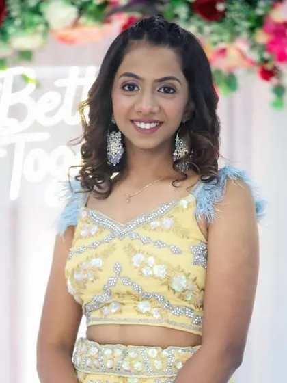 A fresh and youthful look for a wedding guest. The client's yellow lehenga with feather details is fun and festive, and her makeup is kept light and glowing.