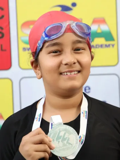 A young swimmer proudly shows her silver medal from the Future Champions Swimming Competition. These moments build confidence for a lifetime.