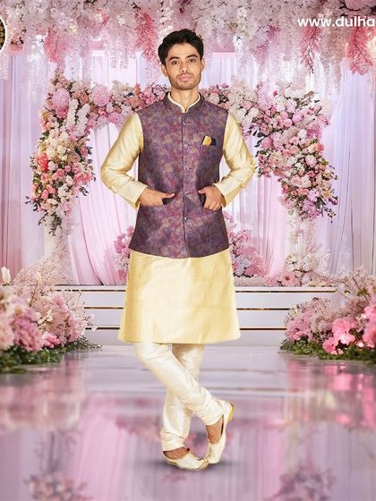 A cream kurta set paired with a purple and gold brocade Nehru jacket, set against a beautiful floral backdrop.