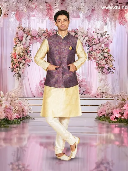 A cream kurta set paired with a purple and gold brocade Nehru jacket, set against a beautiful floral backdrop.
