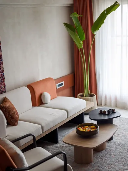 Another view of the living room, showing the large plant and the warm, natural light from the window. The space feels calm, modern, and connected to nature.