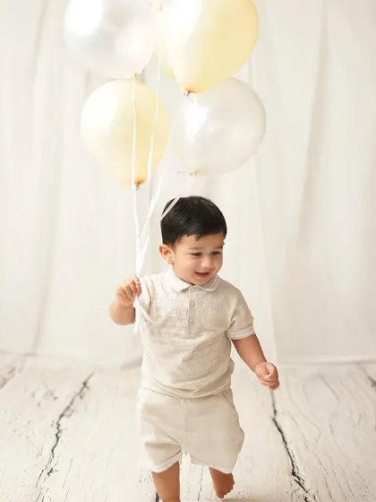 The birthday boy on the move, with a happy smile on his face. The neutral, light-colored balloons add a touch of celebration without being overwhelming.