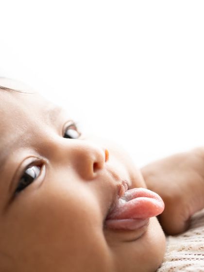 A playful moment captured up close. I love these little details, like a tiny tongue sticking out, that show your baby's emerging personality.