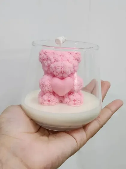 A hand-held view of the pink teddy bear jar candle, giving a sense of its size.