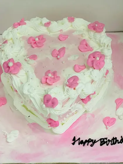 A lovely heart-shaped cake with pink floral details, perfect for a birthday.