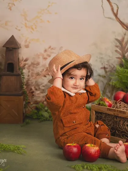 An autumn adventure in the studio. This little one is dressed for apple picking, sitting in a rustic, woodland-themed set complete with a crate of apples and a tiny birdhouse.