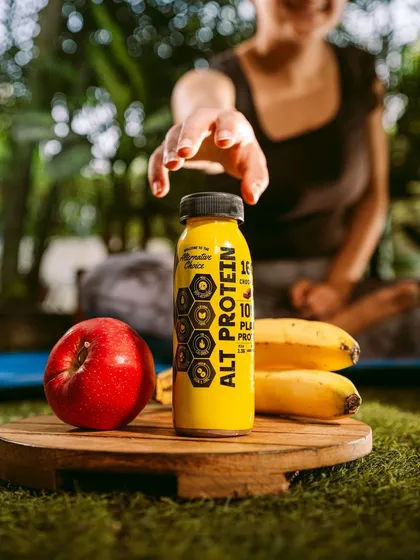 A lifestyle shot for Alt Co. protein drink in a yoga and wellness setting. This image clearly communicates the product's benefits by placing it in the context of a healthy, active lifestyle.