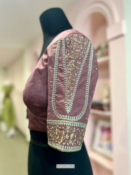A side view of the dusky rose blouse on a mannequin, highlighting the intricate sleeve embroidery.