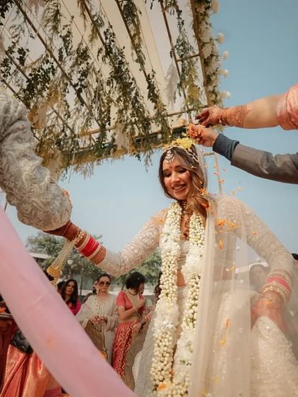 A low angle shot looking up at the bride during the Pheras, as family members shower her with flower petals. This perspective makes the moment feel intimate and special.