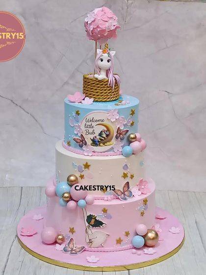 We designed this three-tier chocolate cake to welcome a new baby. It features a unicorn in a hot air balloon, edible images, and a sweet "Welcome Little Bub" message, blending pink and blue for a magical reveal.