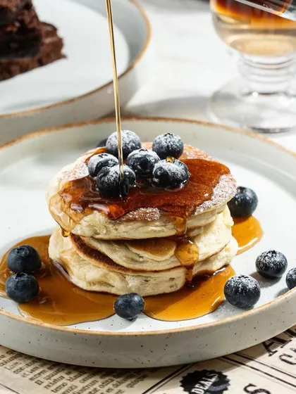 A cascade of maple syrup over a fluffy pancake stack. I use action to bring breakfast shots to life, making them feel warm, comforting, and absolutely essential.
