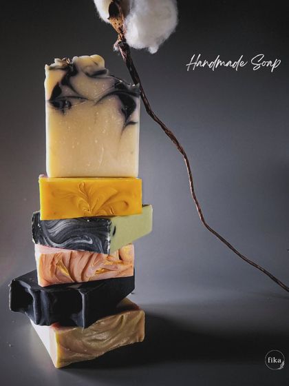 A stack of my handmade soaps, showcasing the variety of natural colors and designs. From deep charcoal to sunny turmeric, each bar is a unique piece of art that transforms your daily bath ritual.