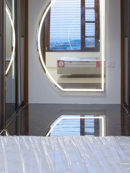 A peek into the walk-in closet from the bedroom. The backlit mirror adds a touch of glamour, while the glossy floor reflects light, making the space feel expansive.