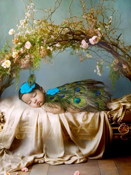 This is one of my most creative setups. A sleeping newborn is dressed as a peacock, resting on a golden bed under a canopy of branches.