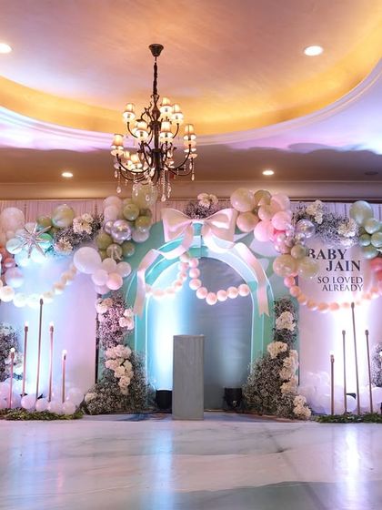 The full stage setup for Baby Jain's shower, featuring pastel balloons, floral arrangements, and elegant arches. A grand setting for a grand celebration.