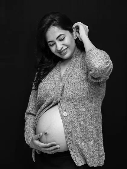 A classic black and white portrait. The mom-to-be is wearing a cozy cardigan, creating a soft, intimate, and timeless image that focuses on her connection with her baby.