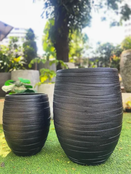 This pair of black FRP planters features a textured, brushed finish. They are highly durable, lightweight, and water-resistant.