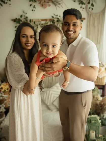 A playful and fun family portrait. The parents hold their baby up to the camera, capturing his adorable smile and creating a joyful, interactive memory.