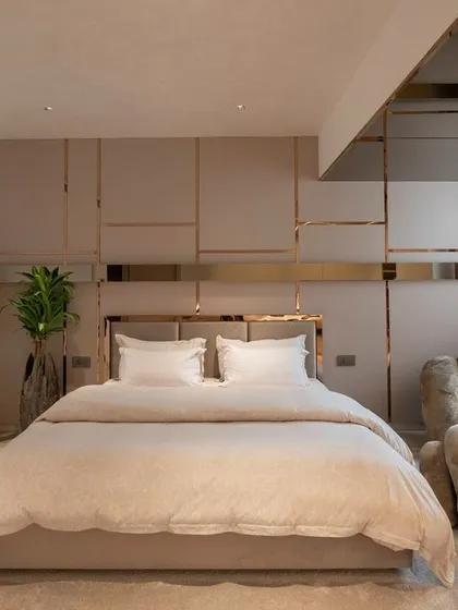 A bedroom should be a personal sanctuary. Here, we used a palette of soft neutrals, refined textures, and custom gold-toned metalwork to create a space that is both luxurious and deeply restful, complete with a unique bear-shaped lounge chair for a touch of playful comfort.